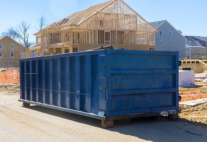 a wide shot of an organized crew filling up a residential dumpster